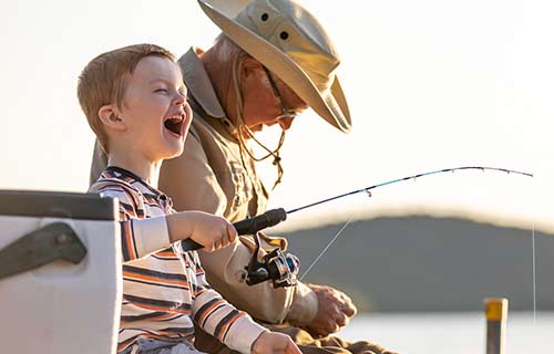 Grandfather and grandchild sitting on a dock fishing.